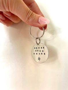 a hand holding a keychain with the words grace upon peace written on it