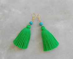 green tasselled earrings with turquoise beads and gold earwires on grey background