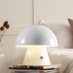 a lamp sitting on top of a bed next to a vase