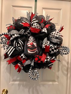 a black and red mesh wreath with a clown face on it's front door