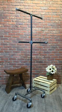 a wooden bench sitting in front of a brick wall next to a metal pipe stand