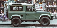 a green jeep is parked on the side of the road in front of graffiti covered buildings