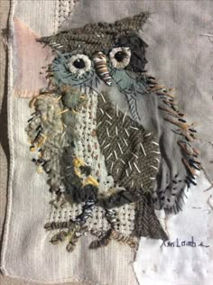 an embroidered owl sitting on top of a piece of fabric