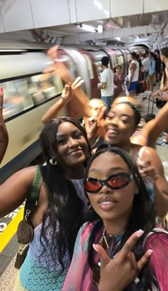 group of people standing in front of a train at a station with their fingers up