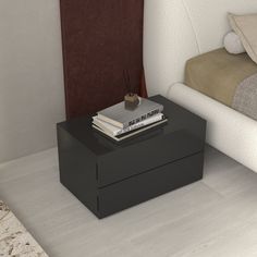 a black table with books on it next to a white chair and bed in the background