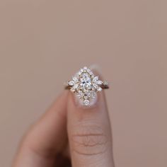 a woman's hand holding an engagement ring with three diamonds on it and the middle finger