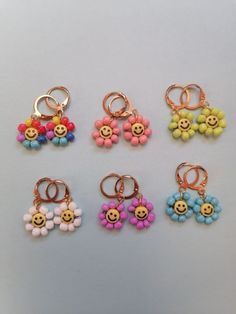 six different types of earrings with smiley faces and flowers in the shape of balls on them