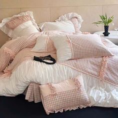 an unmade bed with pink gingham comforter and pillows on top of it