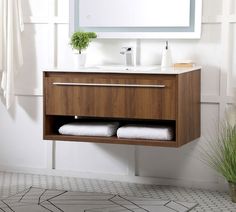 a bathroom vanity with two towels and a mirror above it, in front of a white wall