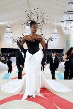 a woman in a black and white gown standing on a red carpet