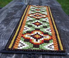 a table runner made out of knitted fabric on top of a wooden table outdoors