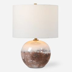 a table lamp with a white shade on it and a brown stone ball underneath the light