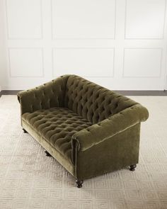 a green couch sitting on top of a carpeted floor next to a white wall