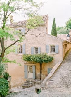 an old stone house with blue shutters on the windows and steps leading up to it