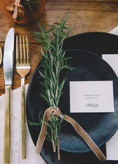 a place setting with silverware, napkins and an empty card on a black plate