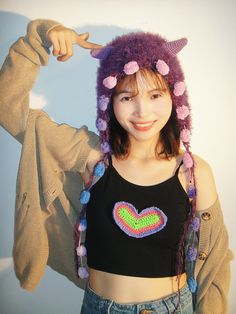 a young woman wearing a knitted hat and holding her hair in the air with one hand