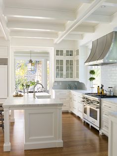 a large kitchen with white cabinets and wood floors