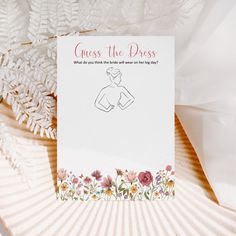 a card that says guess the dress on it with flowers and leaves in front of it