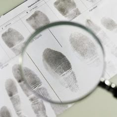 a magnifying glass is sitting on top of a sheet of fingerprints