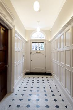 an empty hallway with white walls and black and white checkered flooring on both sides