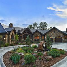 a large stone house with landscaping around the front yard and entry way to the home