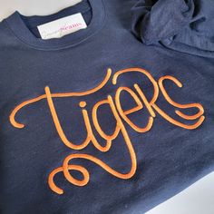 Calling all Auburn Tigers fans! This navy blue sweatshirt with bold orange 'Tigers' embroidery is your go-to choice for game day or everyday style. Stay cozy and show your allegiance to Auburn University. Available in unisex sizes S-3XL. War Eagle! Collegiate Sweatshirt With Screen Print, Relaxed Fit, Orange Cotton Hoodie With Letter Print, Orange Letter Print Crew Neck Hoodie, Varsity Cotton Sweatshirt With Screen Print, Relaxed Fit Screen Print Sweatshirt For Game Day, Orange Crew Neck Sporty Hoodie, Orange Sporty Crew Neck Hoodie, Cotton Sweatshirt With School Spirit Screen Print, Cotton School Spirit Sweatshirt With Screen Print