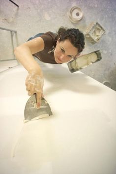 a woman in brown shirt holding a hammer on top of a white counter