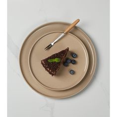 a piece of chocolate cake on a plate with blueberries and a knife next to it