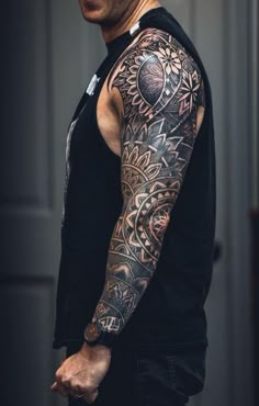 a man with a tattoo on his arm and shoulder is standing in front of a door