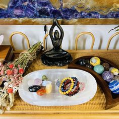 a table topped with lots of different types of rocks and beads next to a buddha statue