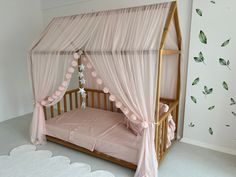 a pink canopy bed with curtains and flowers on the wall next to it in a child's room