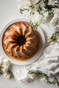 a bundt cake sitting on top of a white plate next to flowers and napkins