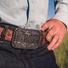 Wild, free, and born country. Show off your roots with this Born Country Attitude Buckle. Silver-toned "Born Country" runs across the center of the buckle with a longhorn steer sitting above. Classic filigree highlights the top and bottom and additional silver-toned borders add texture. Flowers, and silver-toned beads border the outer edge. The whole buckle is antiqued for dimension. Includes a standard 1.5 inch belt swivel. This is the perfect addition to complete your cowgirl wardrobe. This bu Western Concho Belt Buckles For Country Events, Western Concho Belt Buckles For Western-themed Events, Western Adjustable Belt Buckles For Rodeo, Western Style Adjustable Belt Buckles For Rodeo, Engraved Western Belt Buckles For Rodeo, Rustic Concho Belt Buckles For Rodeo, Engraved Western Belt Buckles For Western-themed Events, Rustic Rodeo Belt Buckle With Antique Design, Western Antique Belt Buckle For Rodeo