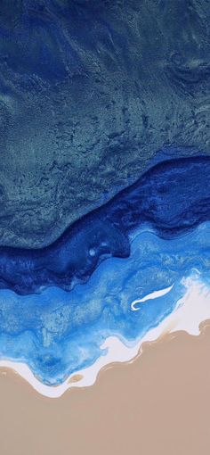 an aerial view of the ocean with blue and white paint on it's surface