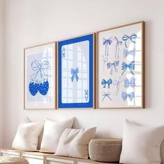 three blue and white paintings hang on the wall above a bench with pillows in front of it