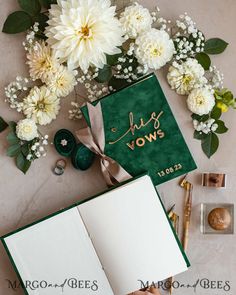 an open book sitting on top of a table next to flowers and other items in front of it