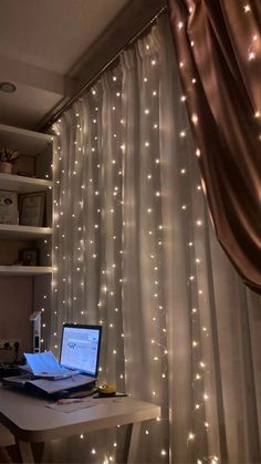 a laptop computer sitting on top of a desk next to a window covered in lights