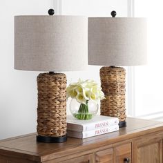 two lamps sitting on top of a wooden table next to a vase with flowers in it