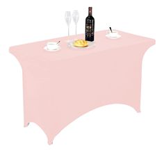 a pink table cloth with wine and food on it