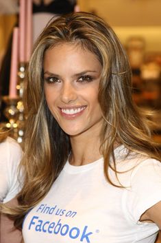 a woman with long hair smiling and wearing a t - shirt that says find us on facebook