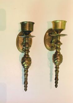 two antique brass candlesticks on a white wall