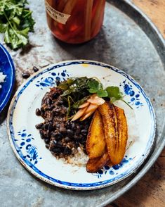 a plate with rice, beans and greens next to a jar of pickled herbs