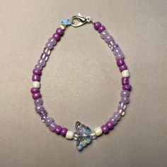 Elevate your ensemble with our Whimsical Butterfly Purple Beaded Bracelet. Handcrafted with care, this charming piece features an assortment of purple beads in various shades, complemented by delicate white pearl-colored beads for an added touch of elegance. At its heart, a delightful butterfly-shaped bead in clear blue and purple tones steals the spotlight, infusing the bracelet with a whimsical allure. Available in two lengths: 18cm and 20cm, this bracelet offers versatility and comfort for everyday wear. Whether worn as a personal statement or gifted to a loved one, our Whimsical Butterfly Purple Beaded Bracelet brings a playful pop of color and style to any outfit. This was also inspired by the K-Pop group BTS and their beautiful song Butterfly Purple Heart Beaded Bracelets, Purple Tiny Beads Beaded Bracelets As Gift, Adjustable Purple Beaded Bracelets With Heart Beads, Bohemian Purple Bracelets With Heart Beads, Purple Beaded Bracelets With Heart Beads For Gifts, Lavender Bracelets With Colorful Beads, Lavender Beaded Bracelets With Tiny Round Beads, Adjustable Purple Beaded Necklace With Heart Beads, Purple Pearl Bracelet Gift