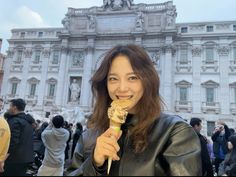 a woman holding an ice cream cone in front of a building