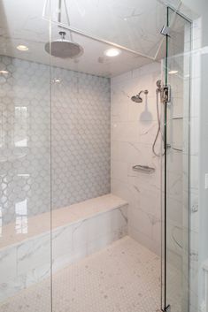 a walk in shower sitting next to a white tiled wall and counter top under a light fixture