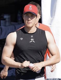 a man wearing a red hat and black tank top is holding a water bottle in his hand