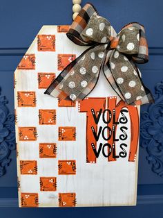 an orange and white door hanger with a bow