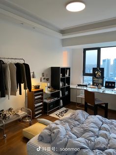 an unmade bed sitting next to a window in a room with clothes hanging on racks