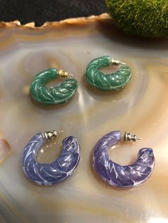 These are beautiful vintage two pairs of earrings, a purple pair and a green pair. They are made of a lucite celluloid plastic hoop with post backs. Lovely design! Back pieces mixed matched, see photos  1" H  These earrings are vintage pieces and have aged patina, wear, scratches, and marks. Please see all pictures and video.  Please let me know if you have any questions  This sale is for two pairs of vintage earrings listed above, any other items shown are for decor and scale purposes only For Green Plastic Earrings For Gifts, Plastic Hoop Earrings For Gifts, Plastic Hoop Earrings Gift, Plastic Hoop Earrings As Gift, Trendy Purple Plastic Jewelry, Plastic Hoop Jewelry Gift, Vintage Green Hoop Earrings Gift, Vintage Green Hoop Earrings For Gift, Vintage Green Hoop Earrings As Gift