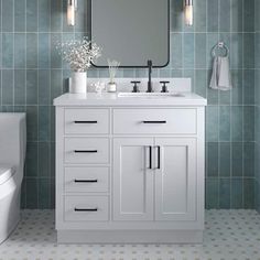 a bathroom with blue tiles and a white sink, toilet and mirror on the wall